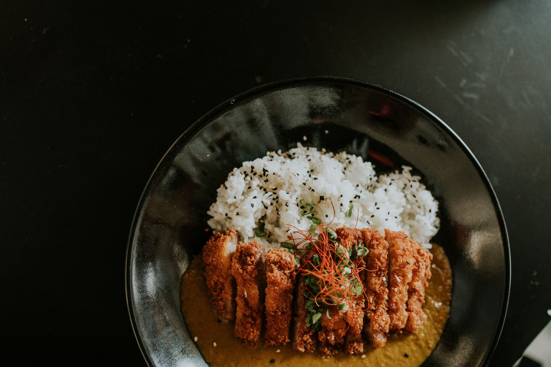 Katsu renyah dengan lapisan tepung krispi, disajikan bersama saus tonkatsu dan nasi putih.
