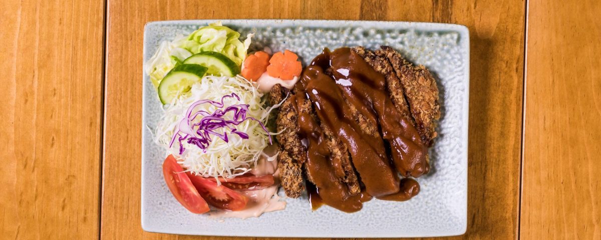Beef katsu renyah dengan saus tonkatsu, dipotong tipis, disajikan di piring putih.