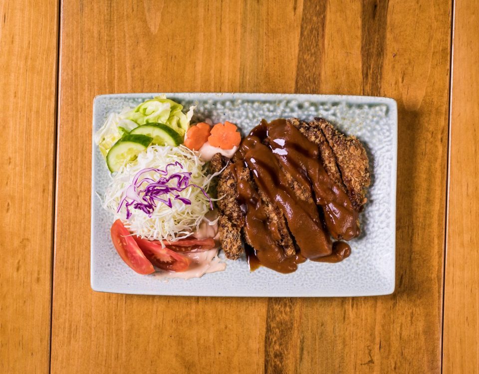 Beef katsu renyah dengan saus tonkatsu, dipotong tipis, disajikan di piring putih.