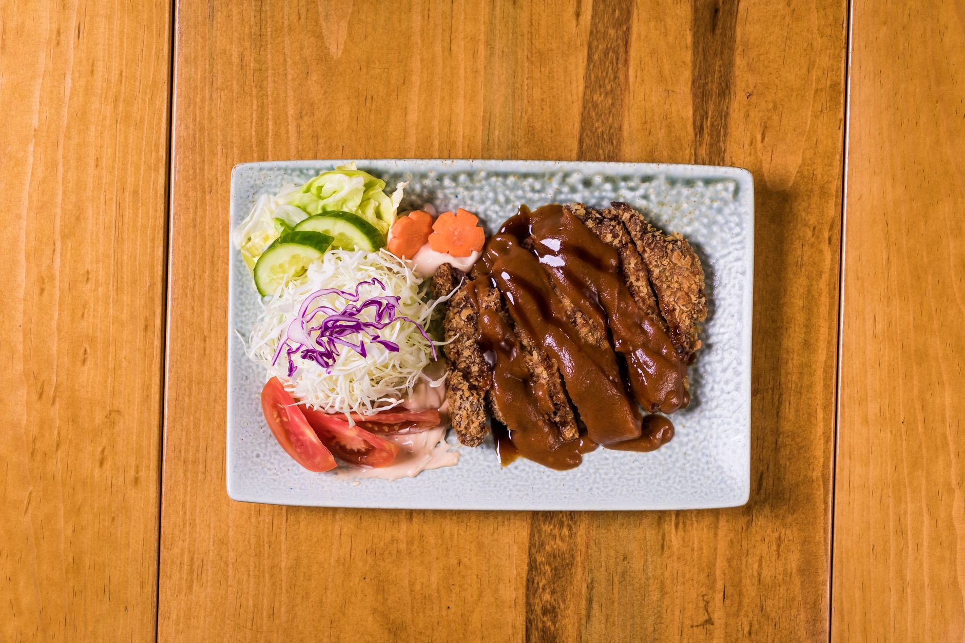 Beef katsu renyah dengan saus tonkatsu, dipotong tipis, disajikan di piring putih.