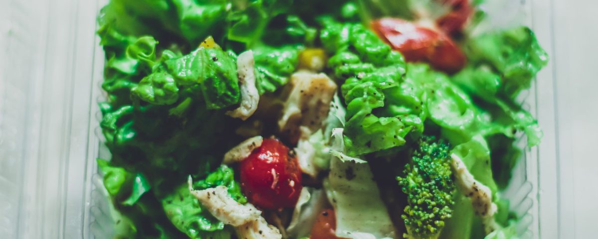 Salad segar berwarna hijau dengan tomat, mentimun, selada, dan dressing zaitun, cocok untuk diet sehat.