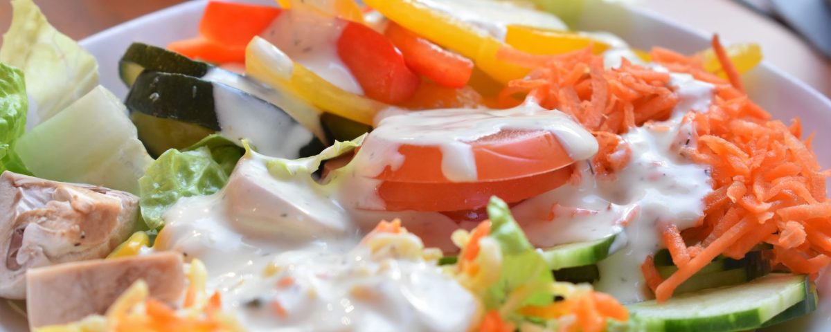 Segar dressing berbasis yogurt dan lemon melapisi salad sayur segar untuk rasa ringan dan sehat.