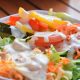 Segar dressing berbasis yogurt dan lemon melapisi salad sayur segar untuk rasa ringan dan sehat.