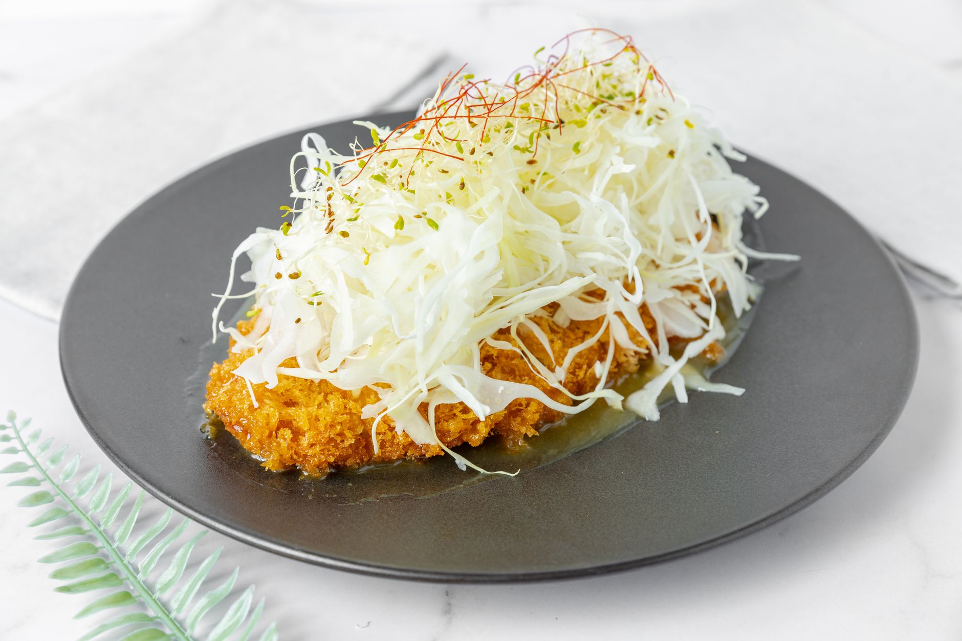 Maranatha Katsu menampilkan sushi roll katsu dengan saus kremas dan taburan wijen di atas piring.